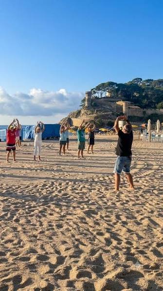 Clase de Tai Chi en la Platja Gran, con el castillo al fondo
